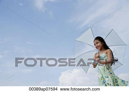 Young girl holding blue umbrella over head View Large Photo Image Picture - Young girl holding blue umbrella over head. Fotosearch