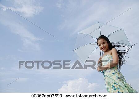 Stock Image - Young girl holding blue umbrella, smiling. Fotosearch