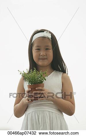 young girl holding plant, smiling, looking at camera View Large Photo Image Stock Image - young girl holding plant, smiling, looking at camera. Fotosearch
