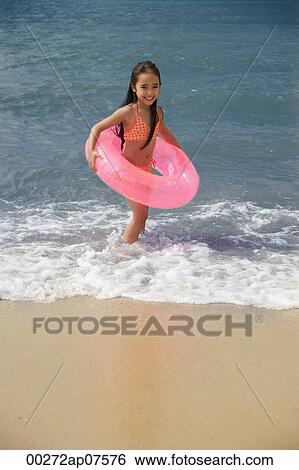 Young girl on beach carrying pink float around waist View Large Photo Image Stock Photograph - Young girl on beach carrying pink float around waist. Fotosearch