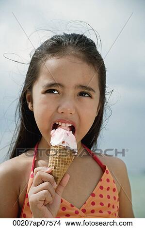 Young girl on beach eating an ice cream cone View Large Photo Image Picture - Young girl on beach eating an ice cream cone. Fotosearch
