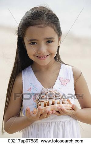 Young girl on beach holding giant conk shell in her hands, smiling View Large Photo Image Stock Photo - Young girl on beach holding giant conk shell in her hands, smiling. Fotosearch
