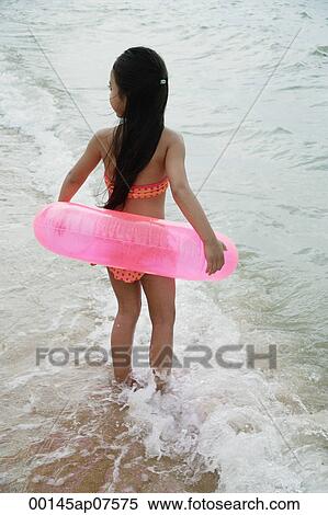 Young girl on beach wearing bikini and carrying pink inner tube View Large Photo Image Stock Photography - Young girl on beach wearing bikini and carrying pink inner tube. Fotosearch