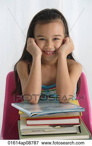 Young girl with books on lap smiling at camera View Large Photo Image Stock Photo - Young girl with books on lap smiling at camera. Fotosearch