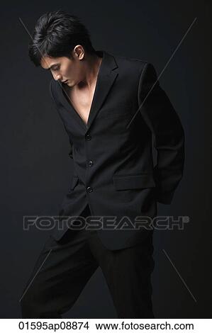 Picture - Young man in black suit looking down. Fotosearch