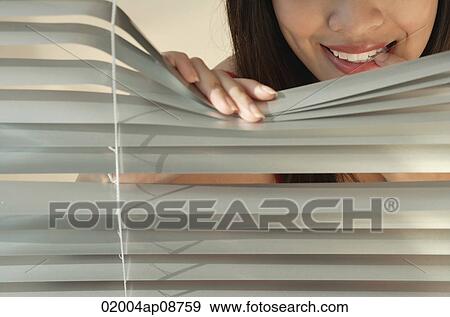 Stock Photo - Young woman behind Venetian blinds. Fotosearch
