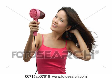 Young woman blow drying hair and looking at camera View Large Photo Image Stock Photo - Young woman blow drying hair and looking at camera. Fotosearch