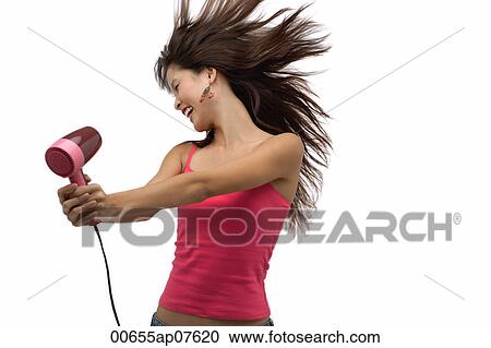Young woman blow drying hair with hair flying View Large Photo Image Stock Image - Young woman blow drying hair with hair flying. Fotosearch