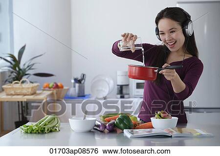Young woman cooking while listening to music View Large Photo Image Stock Photograph - Young woman cooking while listening to music. Fotosearch