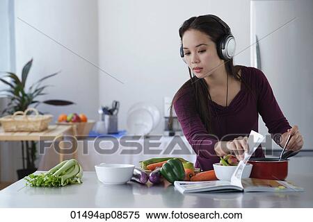 Young woman cooking while listening to music View Large Photo Image Stock Photography - Young woman cooking while listening to music. Fotosearch