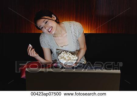 Young woman eating popcorn and watching TV View Large Photo Image Stock Image - Young woman eating popcorn and watching TV. Fotosearch