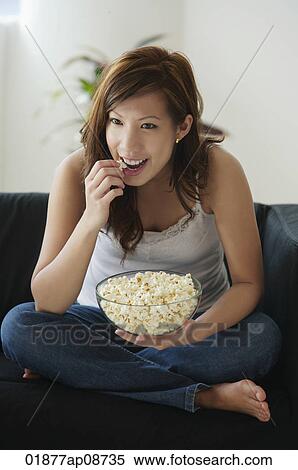 Young woman eating popcorn on sofa View Large Photo Image Stock Photography - Young woman eating popcorn on sofa. Fotosearch