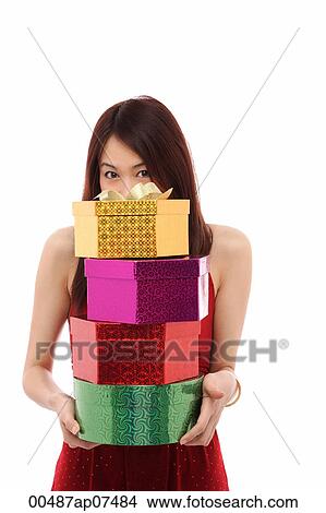 Young woman holding four presents, face hiding behind pile of presents View Large Photo Image Picture - Young woman holding four presents, face hiding behind pile of presents. Fotosearch