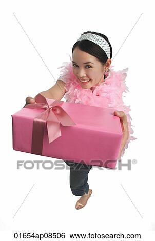 Young woman holding present and smiling at camera View Large Photo Image Stock Photograph - Young woman holding present and smiling at camera. Fotosearch