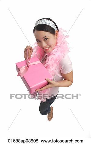 Young woman holding present and smiling at camera View Large Photo Image Stock Photography - Young woman holding present and smiling at camera. Fotosearch