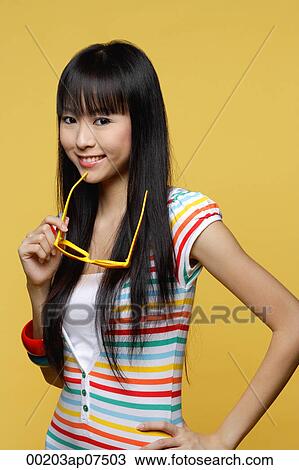 Young woman holding yellow sunglasses, smiling at camera View Large Photo Image Stock Image - Young woman holding yellow sunglasses, smiling at camera. Fotosearch