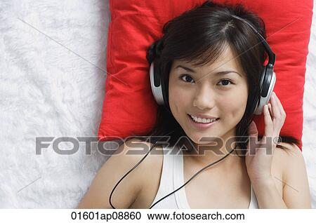 Stock Image - Young woman listening to music. Fotosearch