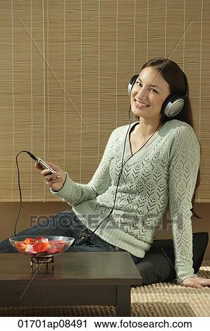 Stock Image - Young woman listening to music. Fotosearch