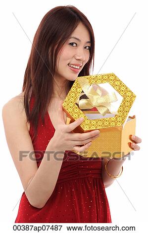 Young woman opening present, and looking at camera View Large Photo Image Stock Photo - Young woman opening present, and looking at camera. Fotosearch