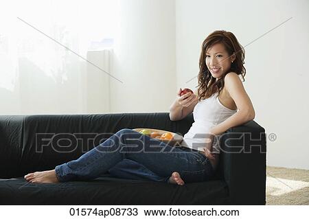 Young woman relaxing on sofa with bowl of fruit View Large Photo Image Stock Image - Young woman relaxing on sofa with bowl of fruit. Fotosearch