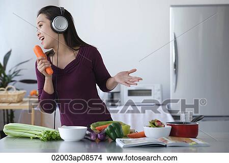Young woman singing into carrot View Large Photo Image Picture - Young woman singing into carrot. Fotosearch