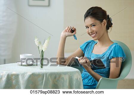Young woman sitting in restaurant, writing into journal View Large Photo Image Stock Image - Young woman sitting in restaurant, writing into journal. Fotosearch