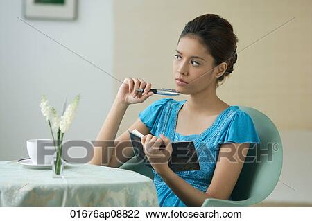 Young woman sitting in restaurant, writing into journal View Large Photo Image Stock Image - Young woman sitting in restaurant, writing into journal. Fotosearch