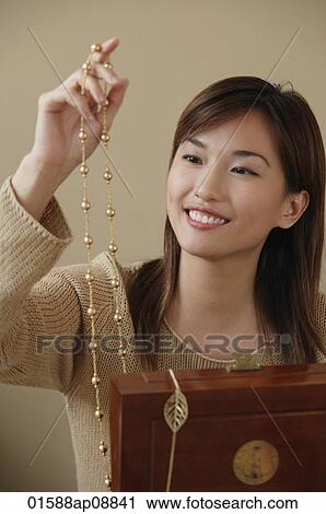 Young woman smiling at necklace View Large Photo Image Stock Image - Young woman smiling at necklace. Fotosearch