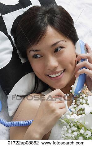 Young woman smiling while on the phone View Large Photo Image Stock Image - Young woman smiling while on the phone. Fotosearch