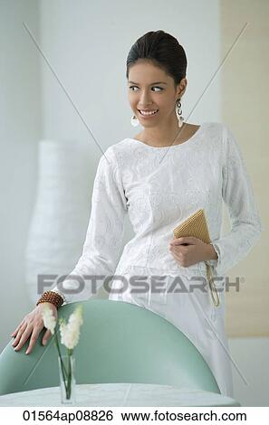 Young woman smiling with hand on chair View Large Photo Image Stock Photograph - Young woman smiling with hand on chair. Fotosearch