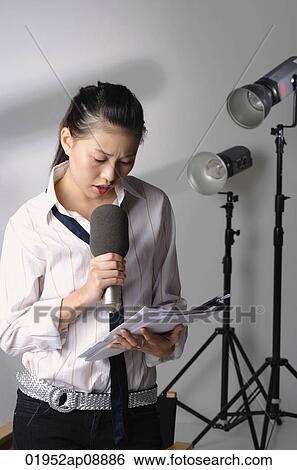Young woman speaking into microphone View Large Photo Image Stock Photograph - Young woman speaking into microphone. Fotosearch