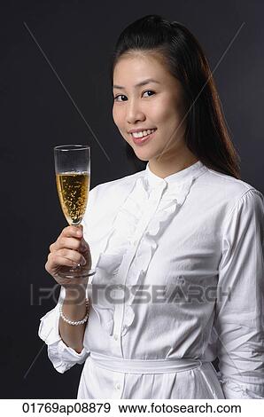 Young woman toasting with champagne and looking at camera View Large Photo Image Stock Photo - Young woman toasting with champagne and looking at camera. Fotosearch