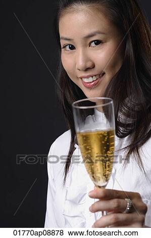 Young woman toasting with champagne and looking at camera View Large Photo Image Stock Photo - Young woman toasting with champagne and looking at camera. Fotosearch