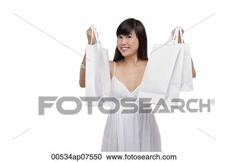 Young woman wearing white dress and holding white shopping bags up in air View Large Photo Image Stock Image - Young woman wearing white dress and holding white shopping bags up in air. Fotosearch