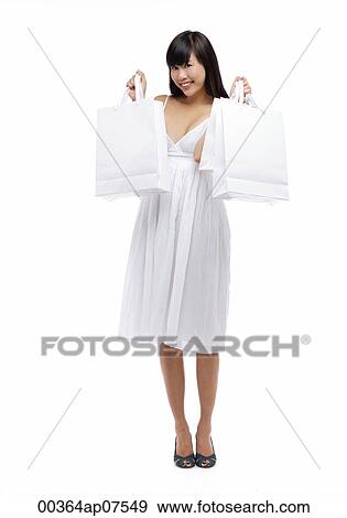 Young woman wearing white dress and holding white shopping bags, smiling View Large Photo Image Stock Photo - Young woman wearing white dress and holding white shopping bags, smiling. Fotosearch