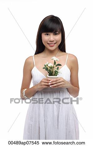Young woman wearing white dress and holing small plant View Large Photo Image Stock Photography - Young woman wearing white dress and holing small plant. Fotosearch
