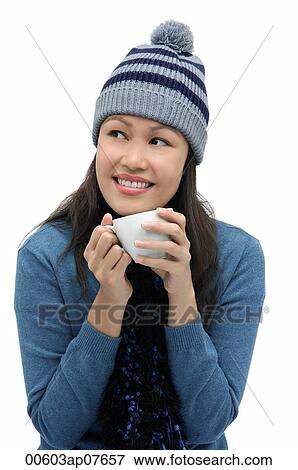 Stock Photo - Young woman wearing winter hat and scarf and holding cup. Fotosearch