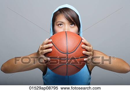 Stock Photography - Young woman with basketball looking up. Fotosearch