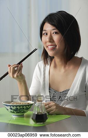 Young woman with chopsticks, eating a bowl of noodles View Large Photo Image Stock Photo - Young woman with chopsticks, eating a bowl of noodles. Fotosearch