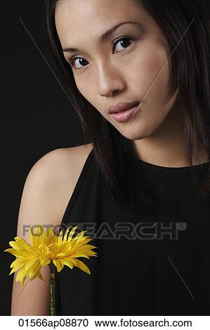 Young woman with flower looking at camera View Large Photo Image Stock Image - Young woman with flower looking at camera. Fotosearch