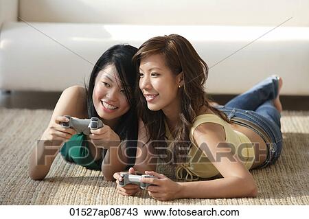 Young women lying on the floor, playing video games View Large Photo Image Stock Image - Young women lying on the floor, playing video games. Fotosearch