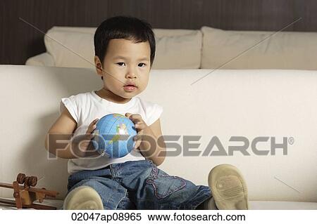 Baby boy holding globe looking at camera View Large Photo Image Stock Photography - Baby boy holding globe looking at camera. Fotosearch