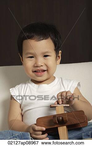 Baby boy holding wooden toy plane smiling at camera View Large Photo Image Stock Photo - Baby boy holding wooden toy plane smiling at camera. Fotosearch
