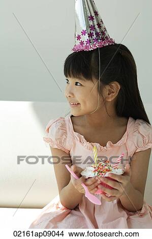 Birthday girl with cupcake looking sideways View Large Photo Image Picture - Birthday girl with cupcake looking sideways. Fotosearch