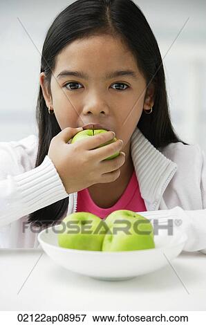 Stock Photo - Girl eating green apple. Fotosearch