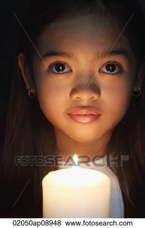 Girl holding candle looking at camera View Large Photo Image Stock Photo - Girl holding candle looking at camera. Fotosearch