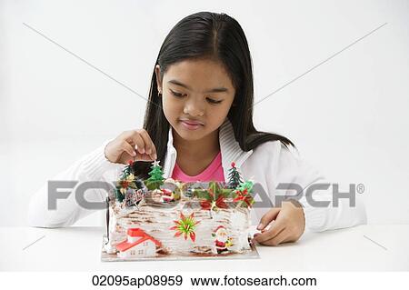 Girl looking at Christmas log cake View Large Photo Image Stock Photo - Girl looking at Christmas log cake. Fotosearch