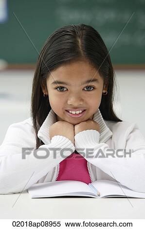 Girl sitting at school desk and smiling at camera View Large Photo Image Stock Photography - Girl sitting at school desk and smiling at camera. Fotosearch