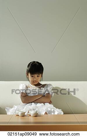 Girl sitting on sofa with tea set on coffee table View Large Photo Image Stock Photo - Girl sitting on sofa with tea set on coffee table. Fotosearch