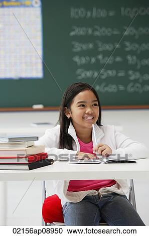 Stock Image - Girl smiling sitting at school desk. Fotosearch